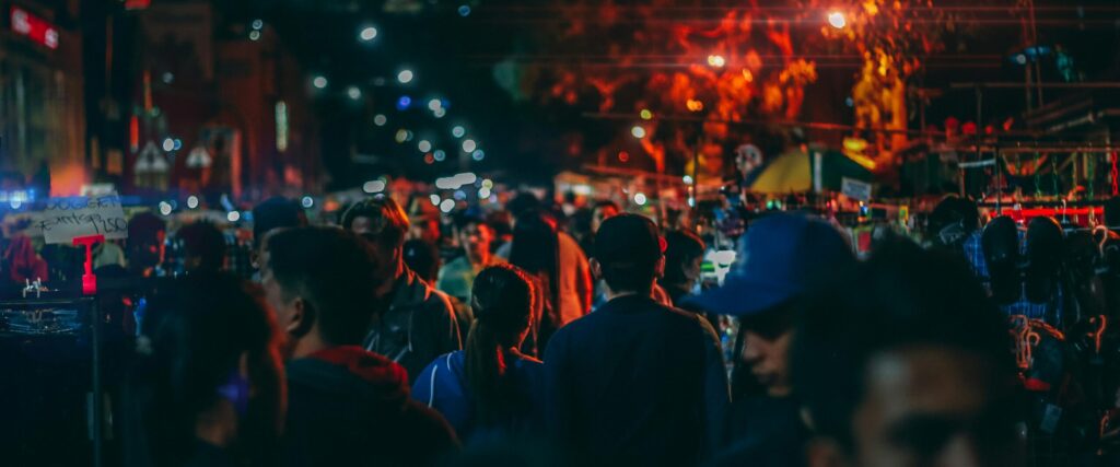 A bustling street market at night with crowds and vibrant streetlights.