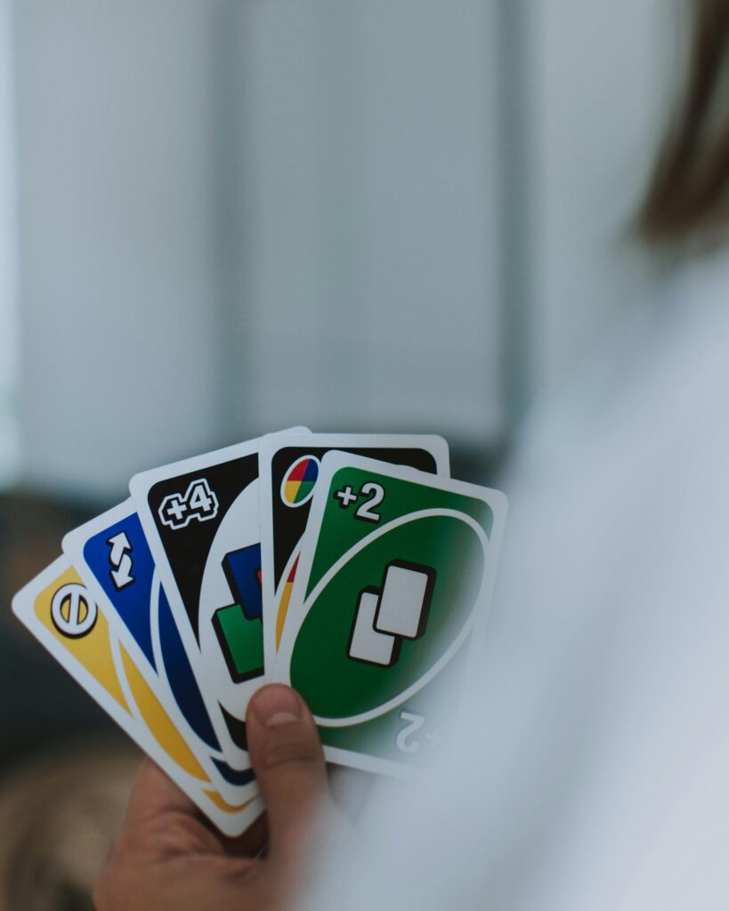 A person holding colorful playing cards, showing a variety of numbers and symbols.