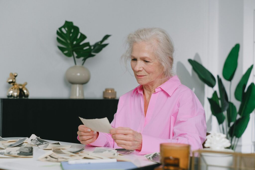 Elderly woman enjoying memories through old photographs, indoors setting.